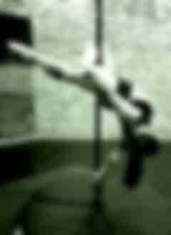 Élève dans une variation de la figure de pole Cross knee, jambe tendue et pieds pointés dans une posture maîtrisée